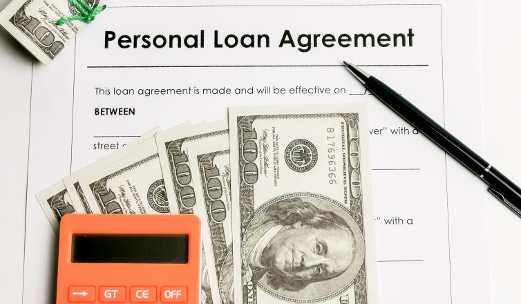 Personal loan agreement form with a pen, calculator, and dollar bills