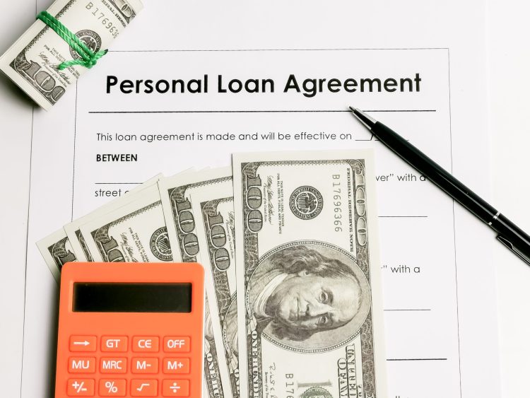 Personal loan agreement form with a pen, calculator, and dollar bills