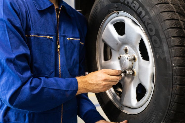 A man adjusting the lugs on a car tire.