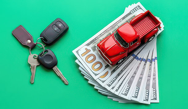 Red toy truck on cash with car keys, representing auto title loans